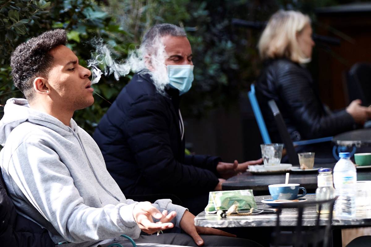 Un joven se quita la mascarilla para fumar en una terraza de Cataluña (Foto: EFE/Alejandro Garc�a)